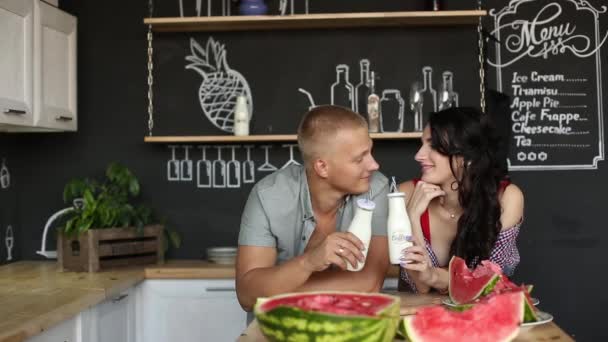 Elegante pareja embarazada bebiendo leche y posando cerca de jugosa sandía . — Vídeos de Stock