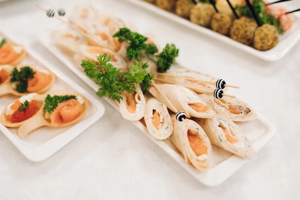 Delicious fish rolls and canape with red caviar served on plates. — Stock Photo, Image