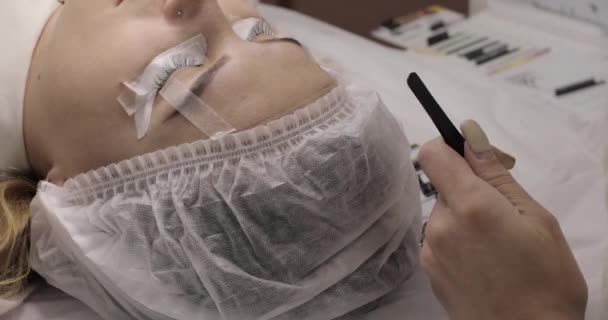 Lash maker realizando procedimento de extensão de pestanas para mulher jovem . — Vídeo de Stock