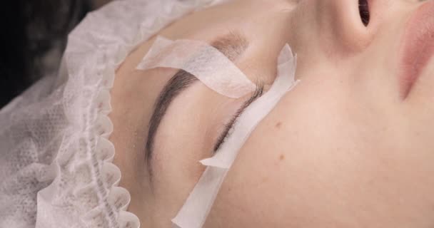 Ojo femenino con cinta adhesiva para el procedimiento de extensión de pestañas . — Vídeos de Stock