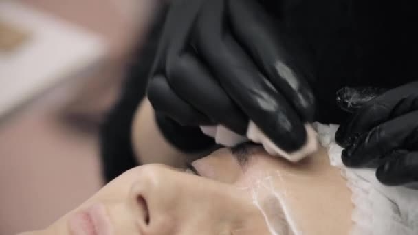 Unrecognizable master in black gloves preparing eyebrows for permanent make-up. — Stock Video