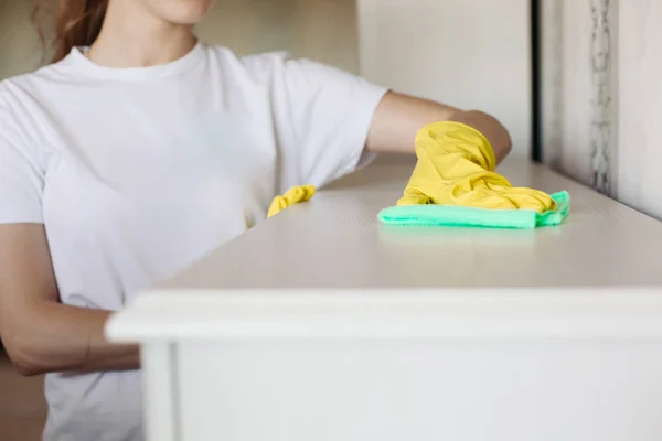 Cultivo de niña usando guantes de goma protectora amarilla, limpiando muebles . — Foto de Stock