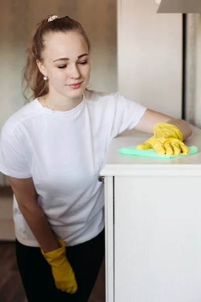 Niña usando guantes de goma amarilla, limpiando muebles con el ruido especial de menta . — Foto de Stock