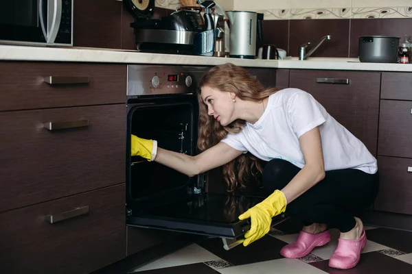 Chica con pelo rizado horno de lavado en la cocina de la mano en el interior . — Foto de Stock