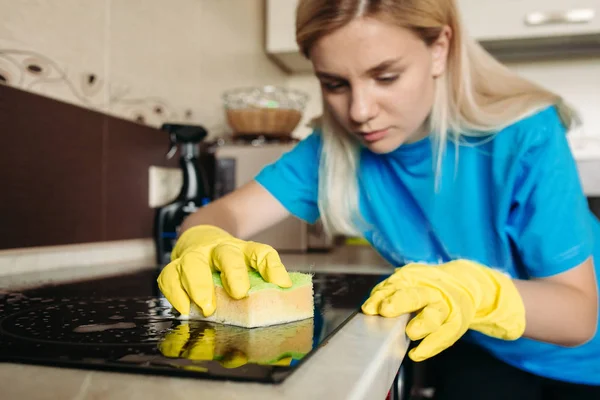 Mujer, vistiendo guante protector con trapo, limpiando estufa eléctrica en casa . — Foto de Stock