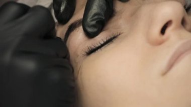 Microblading yordam. Ana güzellik uzmanı çizer ve kaş kalemi ile müşteri düzeltme için notlar. Yakın çekim. 4k, 25 fps.