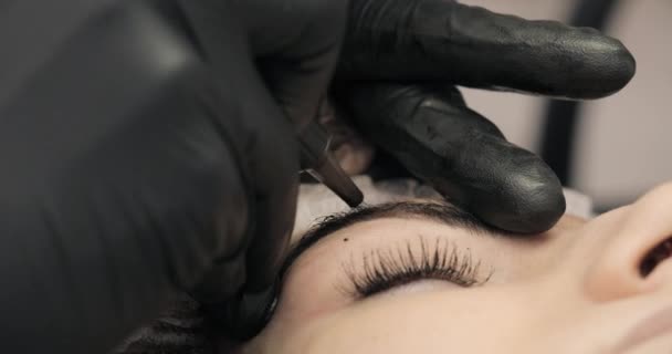 Microblading förfarande. Master kosmetolog ritar och noterar med ögonbrynspenna kunden för korrigering. Närbild. 4k, 25 fps. — Stockvideo