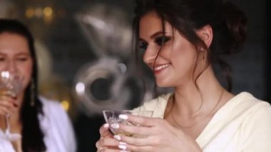 Şirket güzel görünümünü ve pozitif bide mades yatak otel ve şampanya, gözlüklü tarafından sallayarak üzerinde oturan bornoz içinde içme. Gülümseyerek, tavuk parti eğlenceli güzel kızlar.