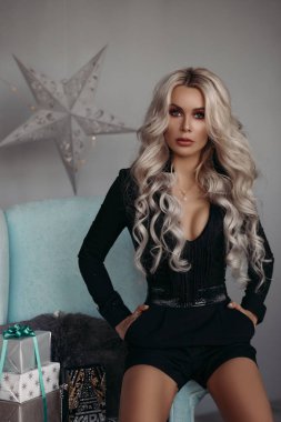 Güzel esmer mini siyah elbise ve Noel odasında gümüş topuklu.