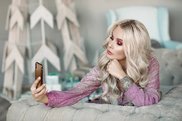 Güzel sarışın yatakta yatarken, telefon tutmak ve selfie yapıyor