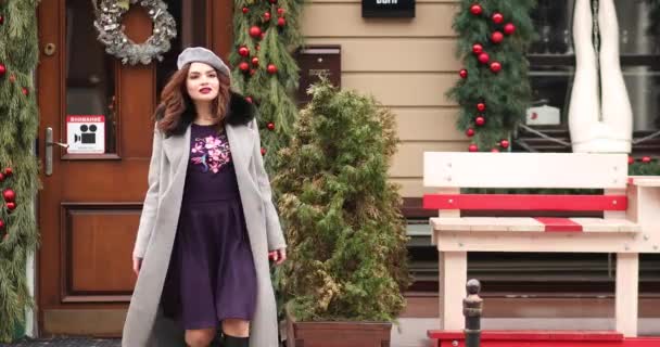 Beautiful girl in grey coat and beret walking towards Christmas shops. — Stock Video
