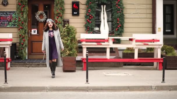 Hermosa chica con abrigo gris y boina caminando hacia las tiendas de Navidad . — Vídeo de stock