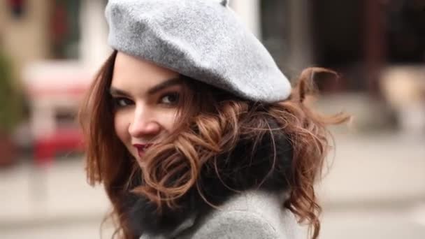 Schönes Mädchen in grauem Mantel und Baskenmütze auf dem Weg zu Weihnachtsgeschäften. — Stockvideo