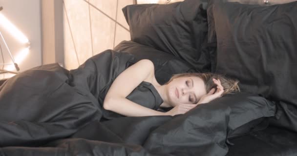 Mooie slanke vrouw in zwarte bed wakker. — Stockvideo