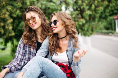 İki güzel trendy teen kız parkta güneş gözlüğü.