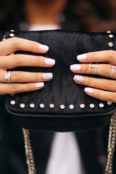 Девушка с ухоженными ногтями с красивым орнаментом в обручальных кольцах с черной меховой сумкой . — стоковое фото