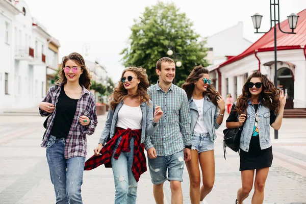 Tredny smiling girlfriends walking along the street with the only man. — Stock Photo, Image