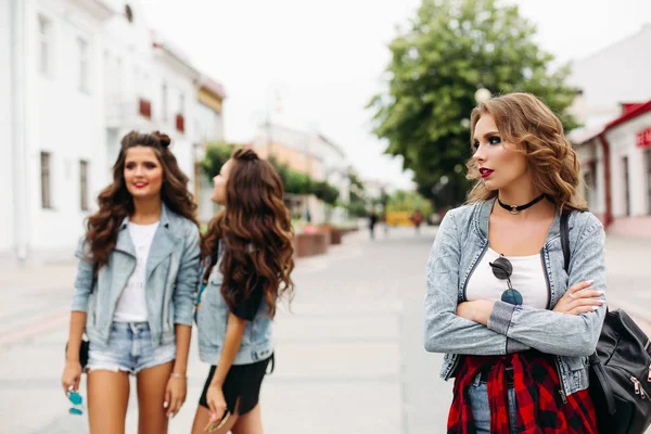 Dwie dziewczyny w tle plotkują o trzecim Nastolatka z make up i fryzurę, szukasz drogi ze smutkiem. — Zdjęcie stockowe