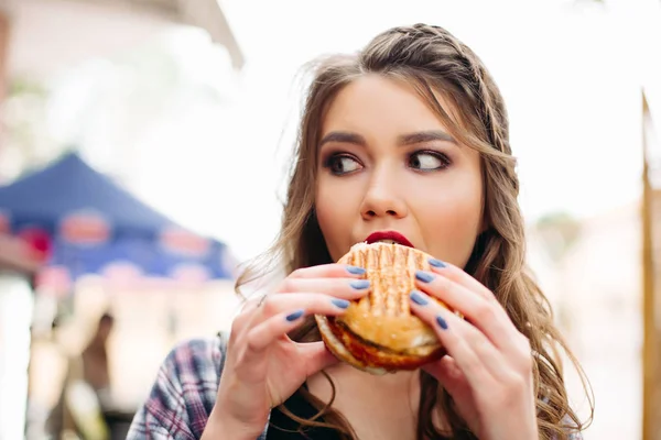 Smakoszem z hamburger patrząc na bok z wstrząśnięty wyrażenie. — Zdjęcie stockowe