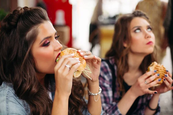 Adolescentes gostando de hambúrgueres no café . — Fotografia de Stock