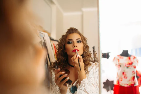 Портрет дівчини наносить помаду на губи і дивиться у дзеркало . — стокове фото