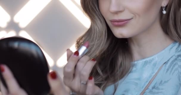 Wanita cantik dengan rambut keriting melihat cermin dan melukis bibir dengan gloss . — Stok Video