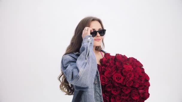 Brunette lady with long hair sniffing bouquet of red roses. — Stock Video