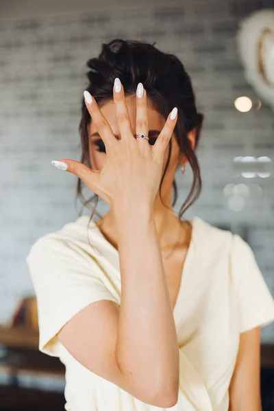 Brunetka nevěsta skrytím obličej a ruce s snubní prsten. — Stock fotografie