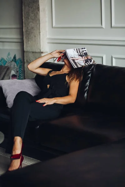 Fáradt nő ül a kanapén, és üzembe magazin a fej. — Stock Fotó