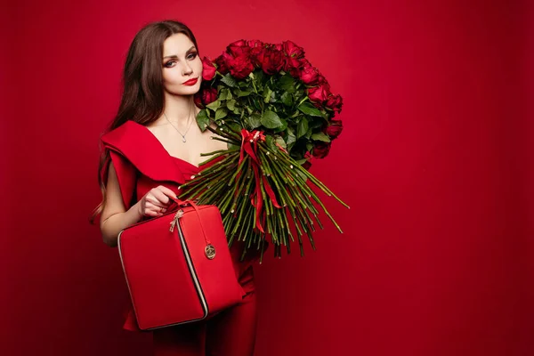 Menina com grande buquê de rosas vermelhas no ombro sonhando . — Fotografia de Stock