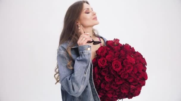 Brünette Dame mit langen Haaren schnüffelt Strauß roter Rosen. — Stockvideo