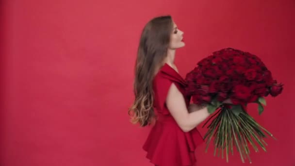 Preciosa mujer en vestido rojo girando con ramo de rosas — Vídeo de stock