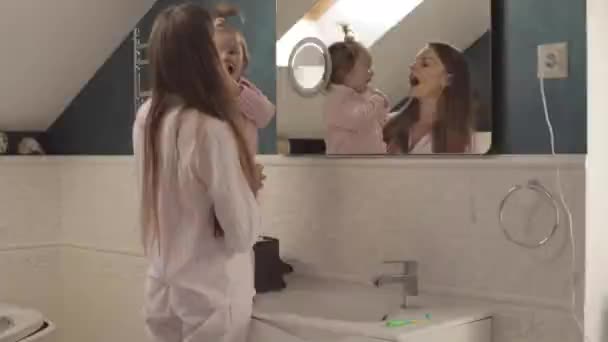 Веселая мать с маленькими семейными зубами в ванной комнате — стоковое видео
