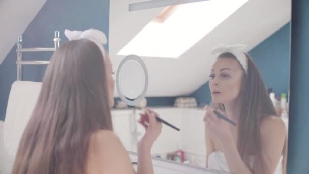 Linda senhora olhando para o espelho e fazendo maquiagem em casa — Vídeo de Stock