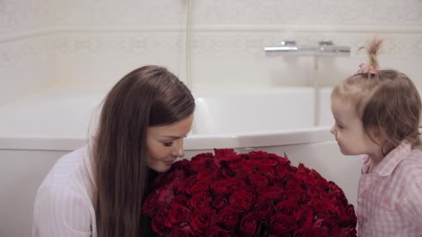 Vista lateral de la madre y la pequeña hija oliendo flores — Vídeos de Stock