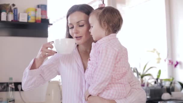 Madre con hija de pie en la cocina y beber café — Vídeos de Stock