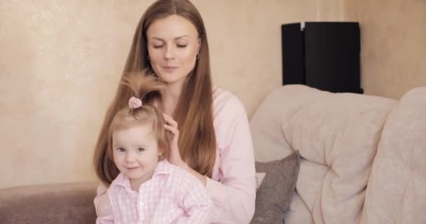 Jonge mooie vrouw houdt weinig kind op haar knieën. — Stockvideo