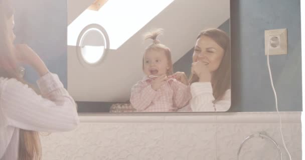 Preciosa madre con poca familia cepillarse los dientes en el baño — Vídeo de stock