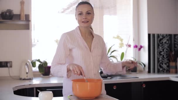 Vista frontal de la mujer bonita cocina en la cocina espaciosa — Vídeos de Stock