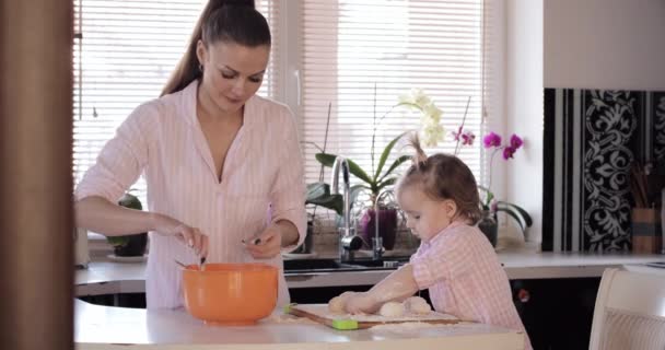 Mãe cozinha em conjunto com a pequena filha na cozinha — Vídeo de Stock