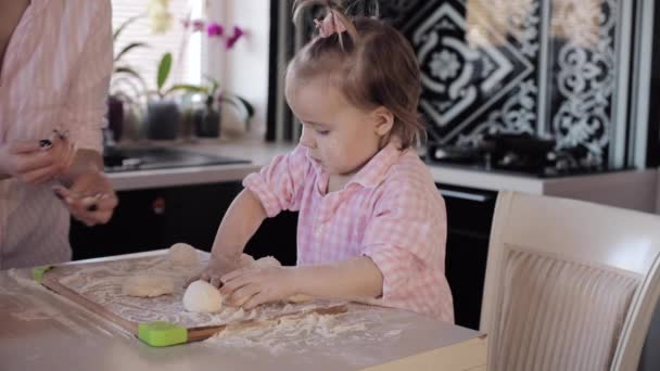 Маленька дівчинка готує з дбайливою матір'ю на кухні — стокове відео