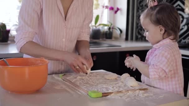 Мати готує разом з маленькою донькою на кухні — стокове відео