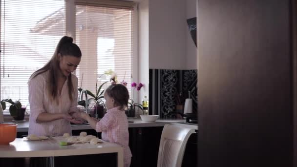 Mãe cozinha em conjunto com a pequena filha na cozinha — Vídeo de Stock