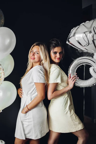 Hermosa novia posando con dama de honor cerca de globos — Foto de Stock