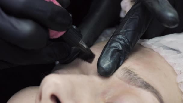 Mestre de tatuagem profissional aplicando maquiagem permanente de sobrancelhas . — Vídeo de Stock