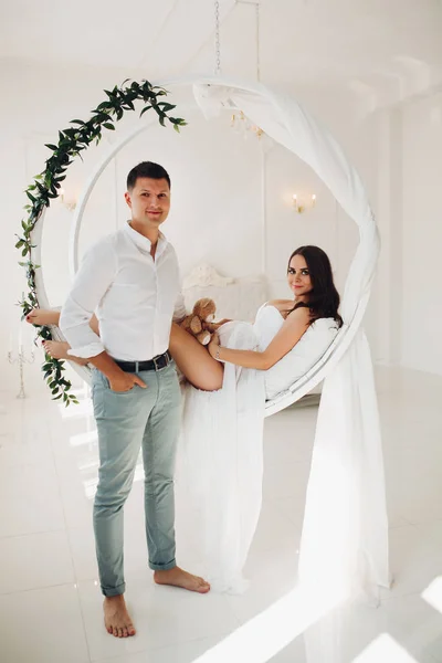 Belo casal de jovens sentados no balanço branco . — Fotografia de Stock