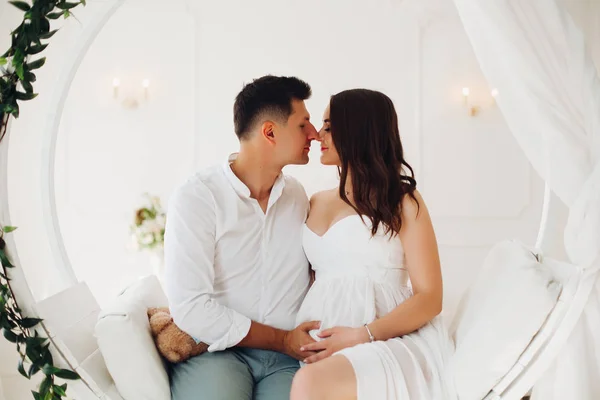 Belo casal de jovens sentados no balanço branco . — Fotografia de Stock