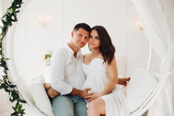 Belo casal de jovens sentados no balanço branco . — Fotografia de Stock