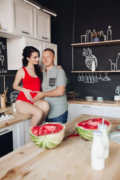 思いやりのある夫の夕食を調理しながら妊娠中の妻にキス — ストック写真