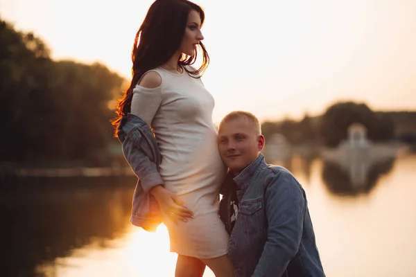 Sorridente uomo felice ascoltando la sua pancia moglie in attesa di bambino . — Foto Stock